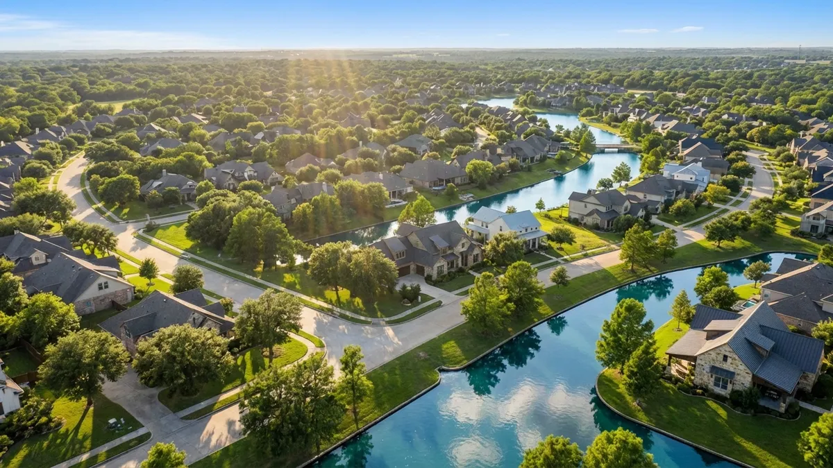 High-angle drone shot over a meticulously planned, vibrant master-planned community. Lush green trees, sparkling waterways, and modern, elegant single-family homes with diverse architectural styles under a bright, clear spring sky. Sunbeams dapple across the scene. Wide shot, 16:9, highly detailed 8k, cinematic lighting, golden hour.