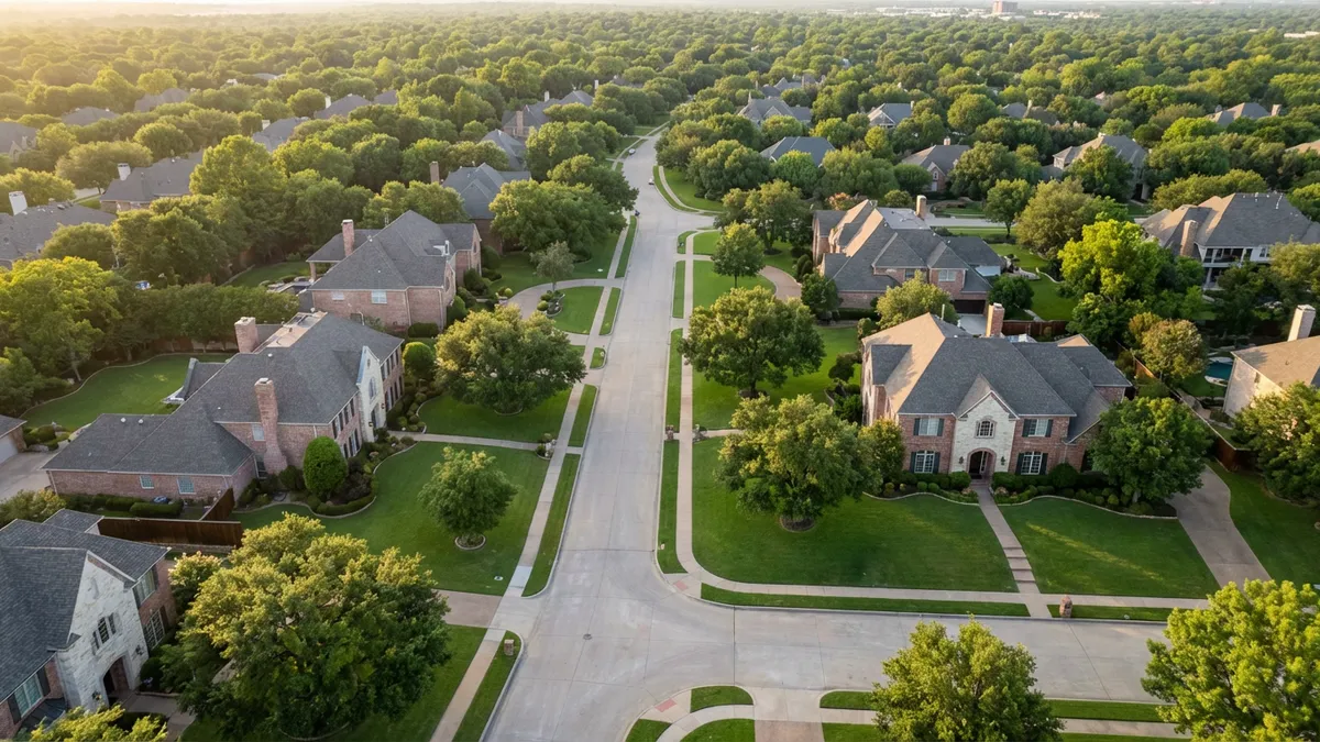 An aerial view of an exclusive, tree-lined residential street in University Park, Texas, during late spring. Elegant, traditional brick and stone luxury homes with manicured lawns are visible. Soft, natural sunlight bathes the scene, creating gentle shadows. The camera is positioned high, capturing a sprawling, affluent neighborhood feel. Cinematic lighting, golden hour, 16:9, highly detailed 8k.